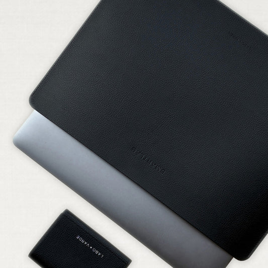 Labovarde Laptop Sleeve in Black — Flat lay view of a silver laptop inside the sleeve next to a small wallet