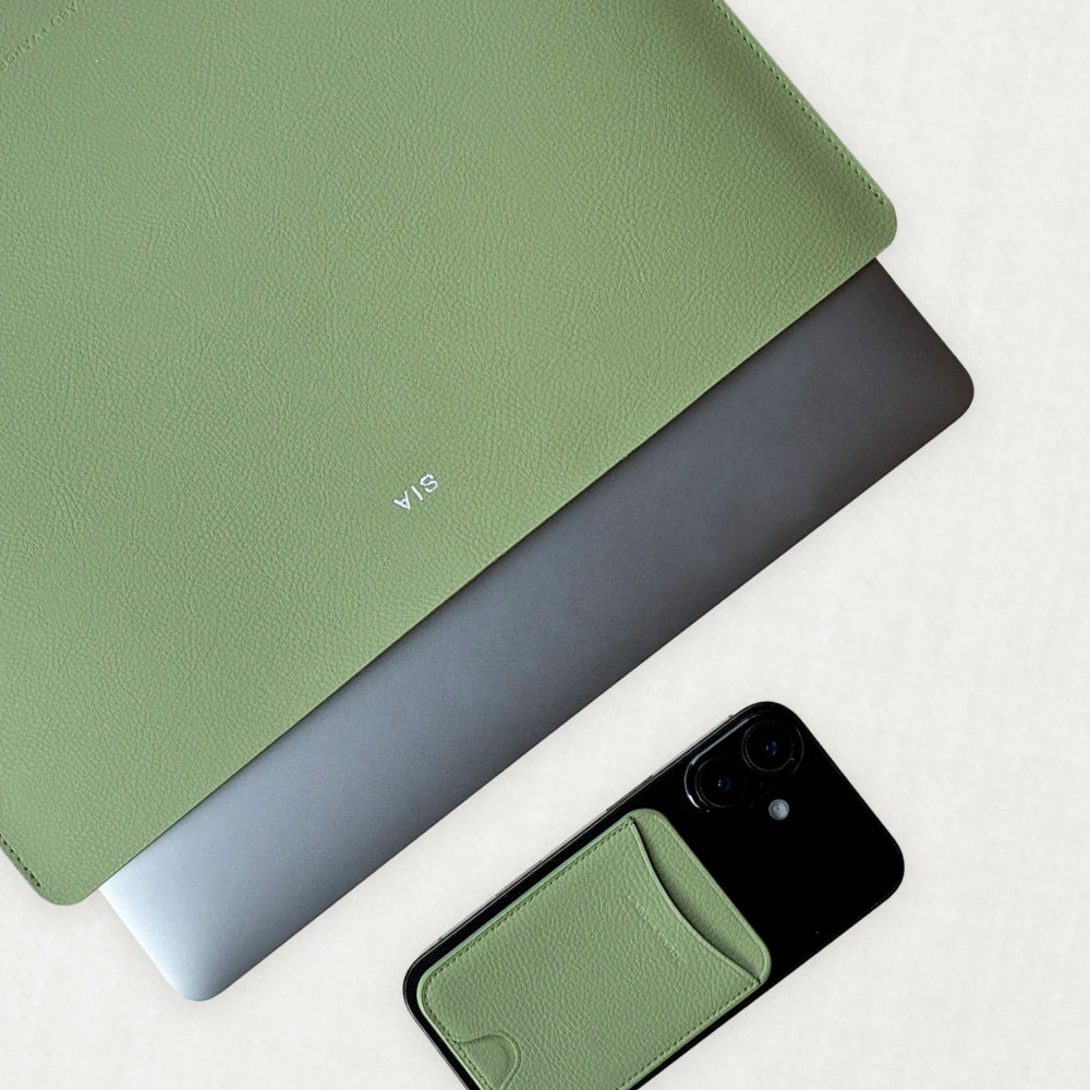 Labovarde Laptop Sleeve in Sage-Green — Flat lay view of a silver laptop inside the sleeve next to a iPhone