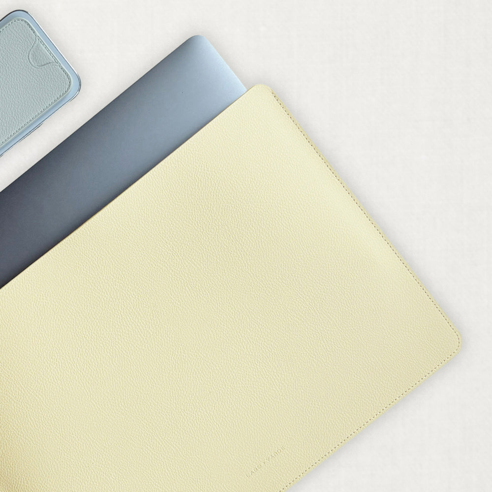 Labovarde Laptop Sleeve in Light-Yellow — Flat lay view of a silver laptop inside the sleeve next to a iPhone